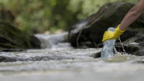 Picking up garbage water plastic nature. Volunteer cleaning river trash pick up litter picking. Cleaning trash mountain river pollution plastic PET bottle plastic garbage shore. Collecting trash shore - Powered by Shutterstock - Get 15% off with code: PIKWIZARD15