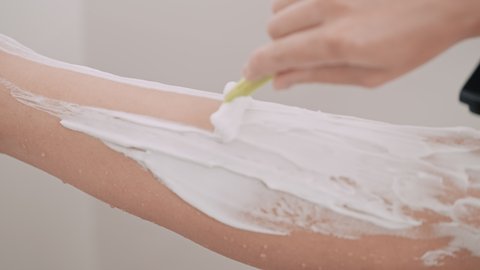 closeup unrecognizable caucasian woman shaving legs holding razor beauty routine at home