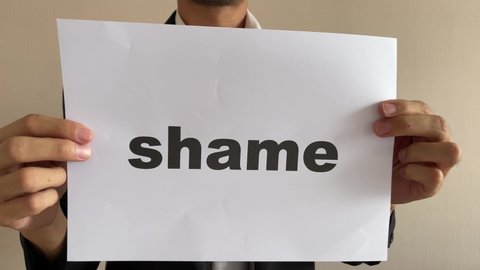 Frustrated asian businessman professional crumpling paper with written message “shame” word. Man in suit and tie having nervous breakdown furiously throwing crumpled paper at work in office