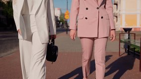 Adult girlfriends walking at street. Closeup shot of legs and hands. Young women walk side by side. Happy girls people spending time together