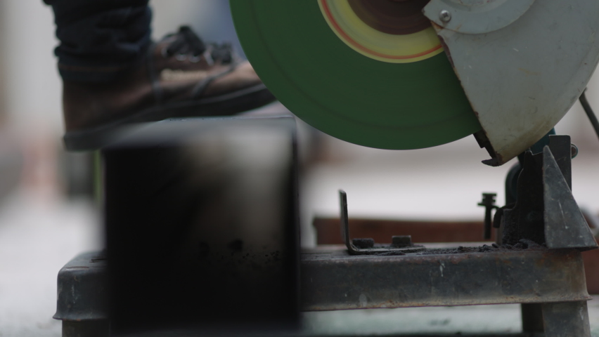 Worker  cutting steel square pipe in constuction site.