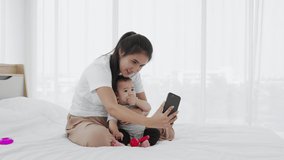 A single mother shows her baby girl to take photos with a smartphone