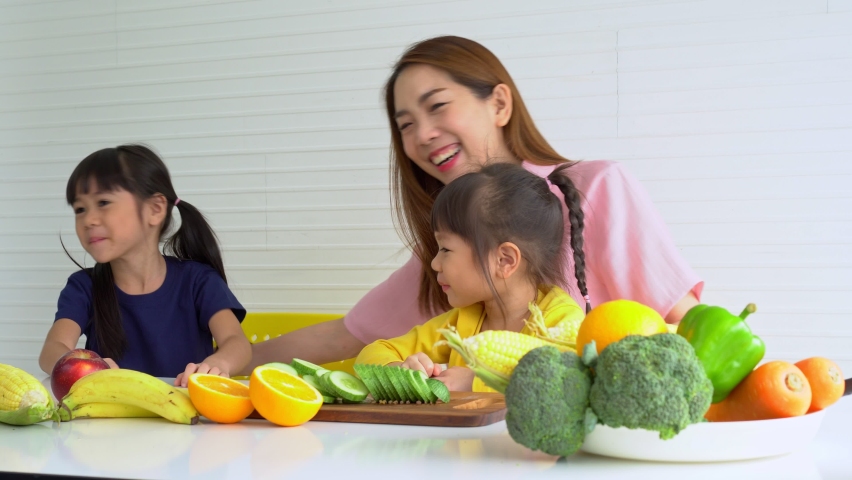 Enjoy Asian mom teaching a little daughter holding knife cut fresh vegetables, Happy family mother and child girl preparing vegetarian vegetable salad at home, Happy family enjoy activity together. | Shutterstock HD Video #1090013927