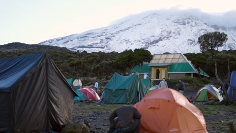 Kilimanjaro. Tanzania. Africa - 12.25.2021 Shira camp in the morning, tourists are going to the ascent, porters are gathering equipment. Many tents on the background of Mount Kilimanjaro