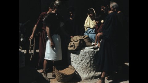 1950s: people in Roman costume inspect sacks of grain. Roman soldier. Man shields lady and child from Roman soldiers.
