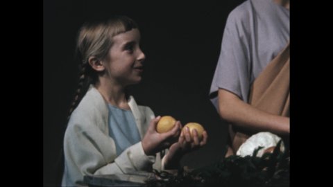 1950s 100 BC: Woman unpacks produce from straw bag, puts on stone wall. Girl holds lemons, talks, smiles. People walk into market, man stands behind counter, looks into woman's bag.