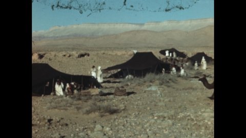 1950s  100 BC: Scrubby desert area, tents, people, camels. Man wears toga, talks to boy, they leave. Woman puts arm around girl, they leave.