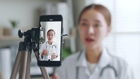 Asian woman doctor making online live streaming broadcast talking over camera recording in hospital, medical and healthcare blogger, vlogger concept - Powered by Shutterstock - Get 15% off with code: PIKWIZARD15