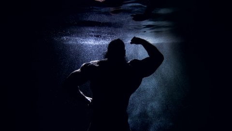 epic underwater shot with dark silhouette of muscular man against sun rays, Poseidon or Neptune god
