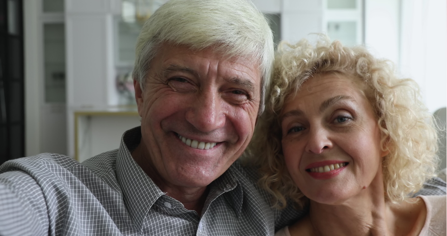 Smiling mature spouses, couple in love hold camera, take selfie, make videoconference, record video, happy faces webcam close up view. Virtual meeting, romantic relations, capture life moments concept Royalty-Free Stock Footage #1090023251