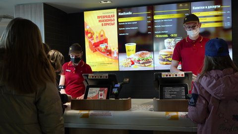 Workers in medical masks serve customers at McDonald's restaurant during a virus epidemic. Lifestyle during pandemic. Minsk, Belarus - may, 2022