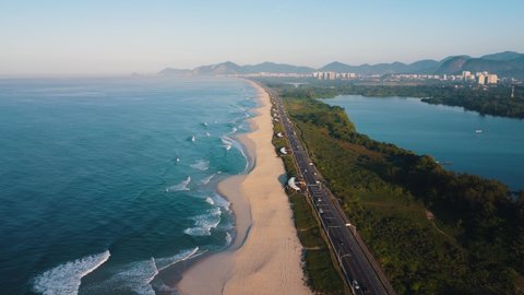 Aerial view of Reserva beach, Marapendi lagoon and car traffic on Lucio Costa avenue. Barra da Tijuca and Recreio, in Rio de Janeiro, Brazil. Sunrise. Sunny day. Drone take. Praia da Reserva.