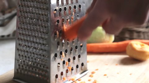 Preparing grating carrot with a metal grater. Ingredient for fresh vegetarian salad
