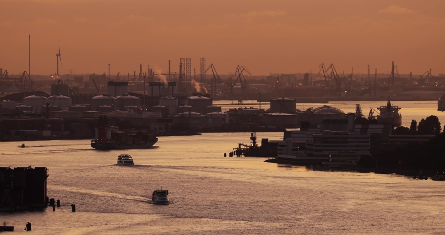 Cargo ship traffic through the ports of Rotterdam, busiest industrial port of Europe. Container ship in twilight, oil storage silos in the background Royalty-Free Stock Footage #1090029131