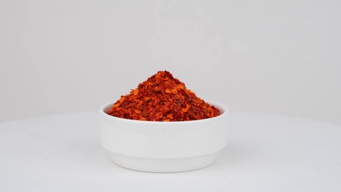 Dried red chili flakes with seeds, isolated on white background. Chopped chili cayenne pepper. Spices and herbs. 