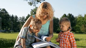 children with mother read a book in the park