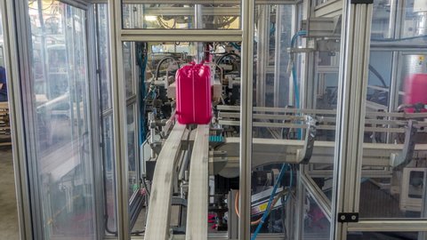 A factory for a red plastic canister production timelapse hyperlapse. The conveyor in the factory. Eco-friendly production.