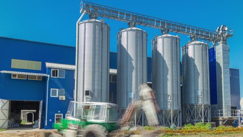 Modern large granary timelapse hyperlapse. Large metal silos. Elevator and factory. Sunny day, the blue sky.