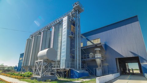 Modern large granary timelapse hyperlapse. Large metal silos. Elevator and factory. Sunny day, the blue sky.