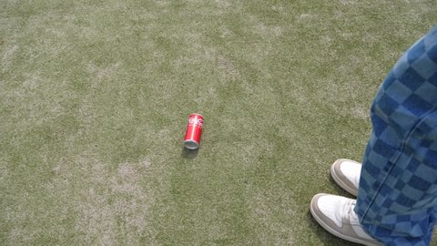 WROCLAW, POLAND - MAY 06, 2022: Teenager boy legs walk kicking empty coca cola can over artificial surface of playground