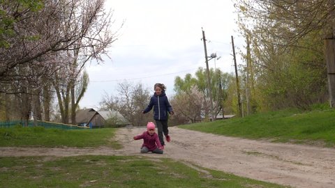 The girl runs away from her sister while playing catch-up and falls. Child injury during active play. Two baby girls are having fun playing. Two sisters. Family