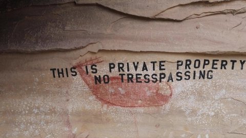 A prehistoric pictograph from thousands of years ago is damaged by graffiti that states "this is private property. No trespassing." The pictograph is located in Nine Mile Canyon, Utah, USA.
