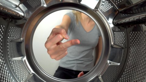chamber is inside drum of washing machine. woman's hand shows fig and an obscene gesture. woman puts her hand inside and shows that she is tired of doing laundry and cleaning. wants to rest