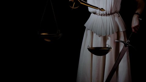 Themis, the goddess of justice blindfolded, with scales and a sword in her hands. A fair trial. Antique goddess, photo on a black background