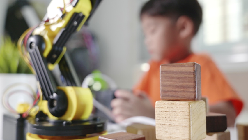 Happy Asian little kid boy using remote control playing robotic machine arm for pick up wood block, Funny child learning successful getting lesson control robot arm, Technology science education Royalty-Free Stock Footage #1090042853