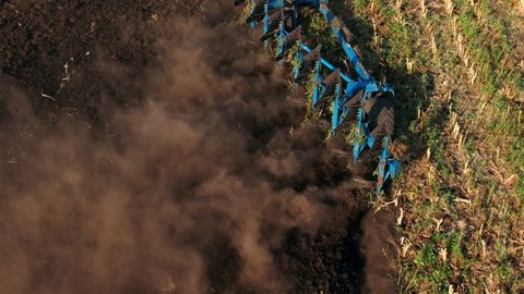 Aerial view of a agricultural tractor with a plow during field work on agricultural field in sunset light. Agriculture industry, cultivation of land. Concept production food.