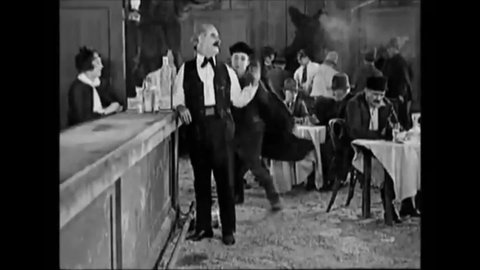 CIRCA 1925 - In this silent comedy, a lightweight drinker falls to the floor after drinking a shot in a saloon.
