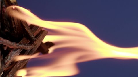 The wooden fire is orange, and the smoke of the fire from the mustard tree is on a blue background. Close-up of a flame with white smoke. Slow motion, 4K.