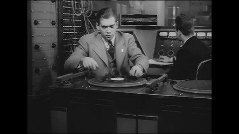 CIRCA 1942 - Two men put on a record in an army radio station and make adjustments.