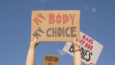 Protesters holding signs My Body My Choice, Abortion Is Healthcare and Bans Off Our Bodies. People with placards supporting abortion rights at protest rally demonstration.