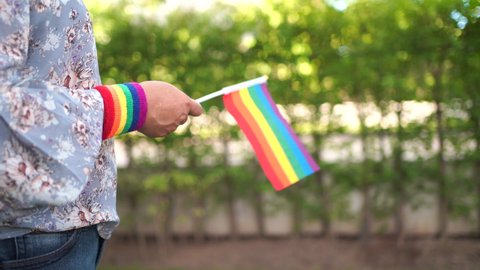 Asian lady holding rainbow color flag, symbol of LGBT pride month celebrate annual in June social of gay, lesbian, bisexual, transgender, human rights.