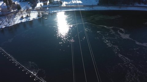 Beautiful clip above high voltage power lines from Nore powerplant and over mountaintop - Forward moving aerial with tilt up revealing bright sun - Illustrating transportation of electricity Norway
