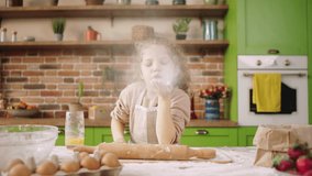 At modern kitchen island charismatic little girl blowing the flour in front of the camera while preparing some delicious dessert for all family members - Powered by Shutterstock - Get 15% off with code: PIKWIZARD15
