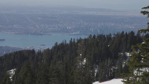 View of Top of Grouse Mountain Ski Resort with the City in the background. North Vancouver, British Columbia, Canada. Sunny Day. Slow Motion