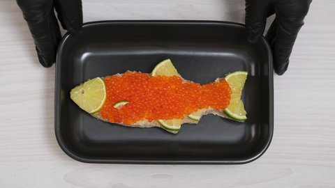 Sandwich with red caviar in shape of fish with lemon put on plate. Expensive healthy food concept close-up slow motion. Sandwiches bread or toast with salmon caviar salted roe. Fish dish. Sea food