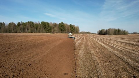 Tractor plowing field, drone view. Cultivated land and soil tillage. Tractor with disc cultivator on cultivating. Agricultural tractor on field cultivation. Tractor disk harrow on plowing field. 