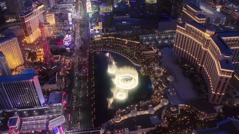 Aerial 4K high angle view of Strip cityscape with cinematic bright colorful night city lights view. Scenic Bellagio fountains show illuminated at night. Resort Casinos on Las Vegas Strip, USA Apr 2022