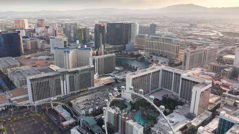 Aerial evening video of High Roller Wheel in Las Vegas, Paris, Cosmopolitan, Cesar, Bellagio resorts and casinos. STRIP traffic, colorful ad screens, modern hotel buildings in Las Vegas USA Apr. 2022