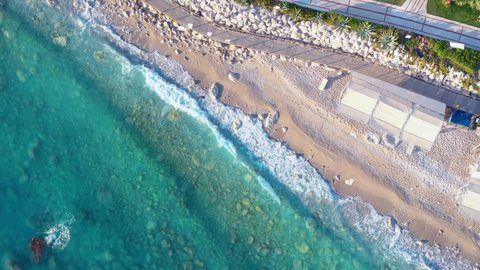 Aerial view of blue sea, rocks in clear water, white sandy beach at sunset in summer. Top view from drone of tropical sea coast, stones in azure water, waves. Oludeniz, Turkey. Tropical seascape