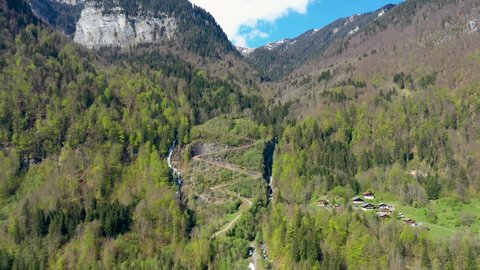 Stunning drone footage of Alpine Mountains, forests and waterfalls. Chalets nestle in the beautiful landscape near Sixt fer Cheval in the French alps.