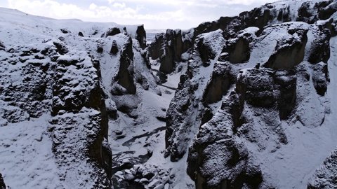 Stunning view of popular canyon Fjaðrárgljúfur in southern Iceland near route 1 with snow-covered rocks, steep cliffs and winding Fjaðrá river on sunny winter day.