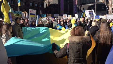 AMSTERDAM, NETHERLANDS – FEBRUARY 27 2022: Europe politics and protest. Ukrainians and others wave national flag and chant 'stop Putin, stop war', during support rally against Russian invasion.