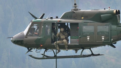 Zeltweg, Austria SEPTEMBER, 6, 2019 Assault soldiers in combat gear descend from a rope tied to a hovering helicopter. 4K close up side view. Agusta Bell AB 212 UH-1N Twin Huey of Austrian Air Force