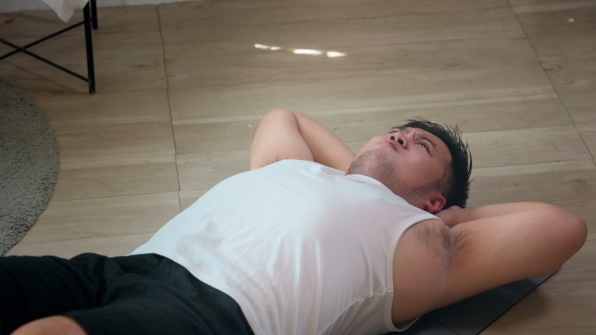 Close-up of a chubby man endeavor to do sit-up at home for weight loss and burning fat calories training. Asian male people Plus size in sportswear workout for good body and healthy Royalty-Free Stock Footage #1090070711