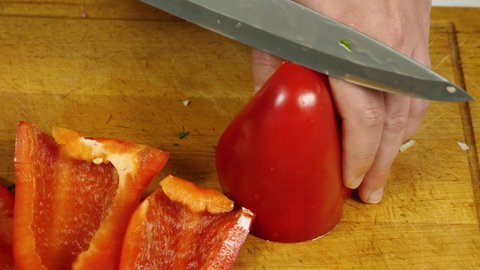 Close-up of a cook cutting red bell peppers on a kitchen board. View from above. The concept of delicious and healthy food