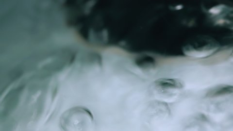 CU, macro view, slow motion: clear water flow with air bubbles runs down through drain hole in modern metal sink extreme closeup